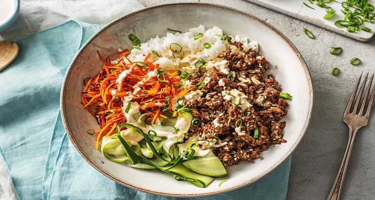 a bowl filled with rice, meat and veggies on top of a table