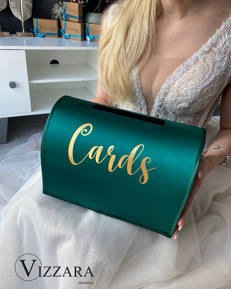 a woman in a wedding dress holding a green box with the word cards on it