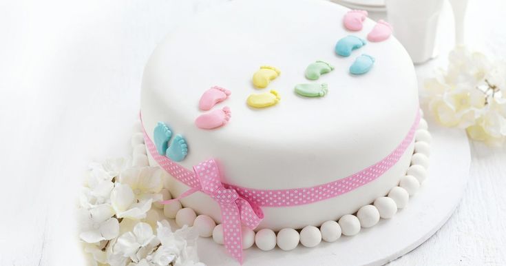 a white cake with pink, yellow and blue decorations on it sitting on a table