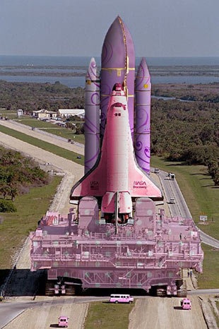 a large pink rocket sitting on top of a runway