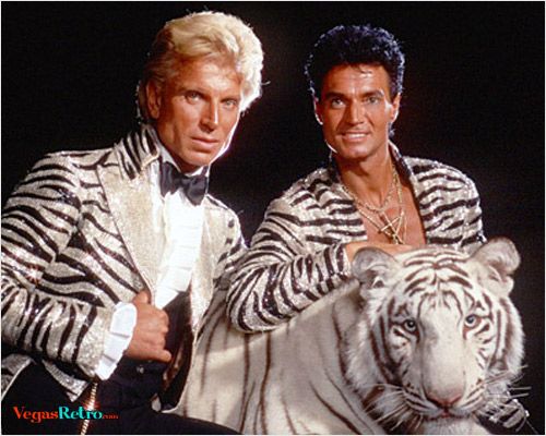 two men dressed in white tiger costumes pose for a photo with one of them holding a large white tiger