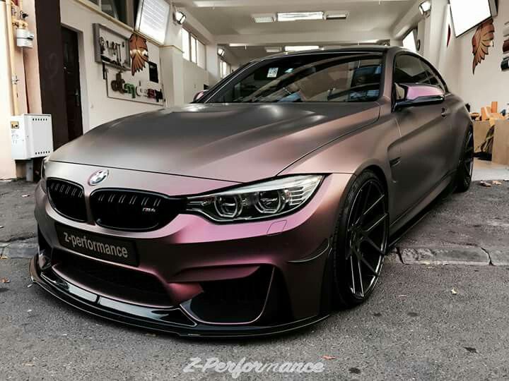 a car parked in front of a building with purple paint on it's hood