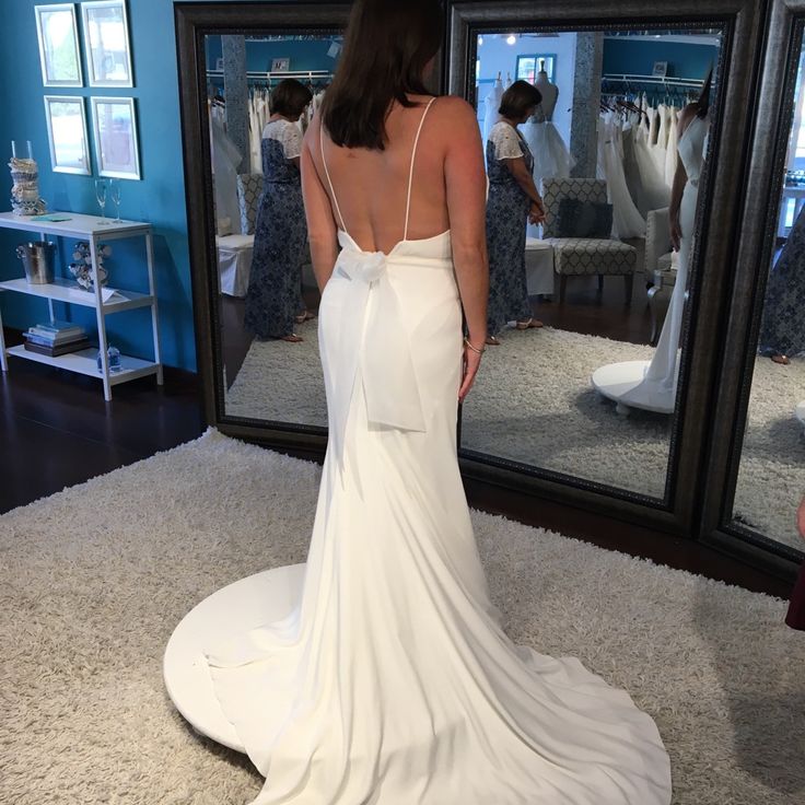 a woman standing in front of a mirror wearing a white dress