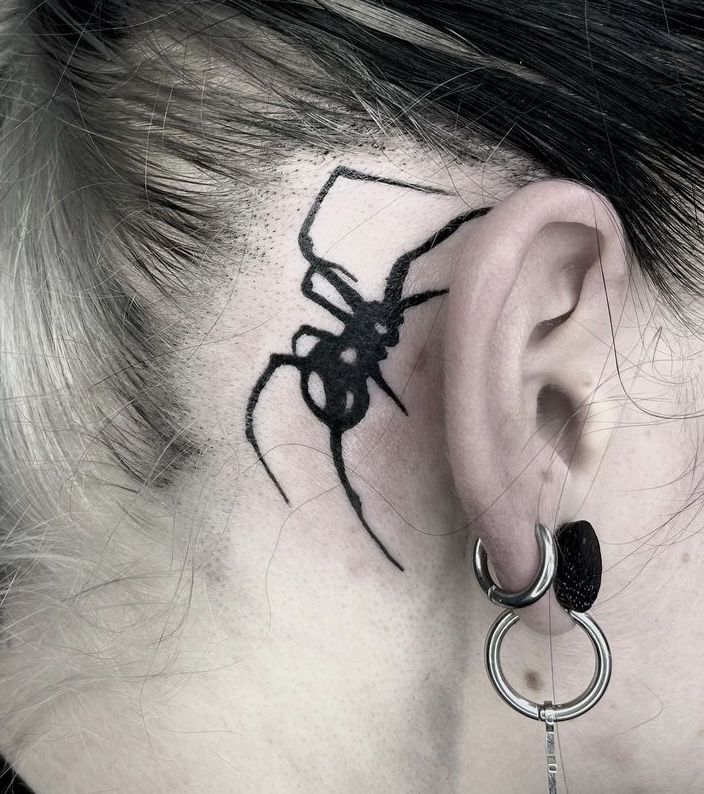 a woman with a spider tattoo on her behind the ear