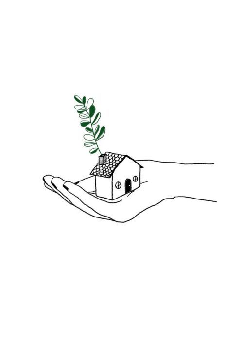 a hand holding a small house with a plant growing out of it's roof