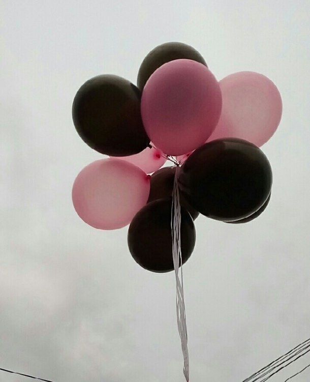 a bunch of balloons floating in the air on a cloudy day with power lines behind them