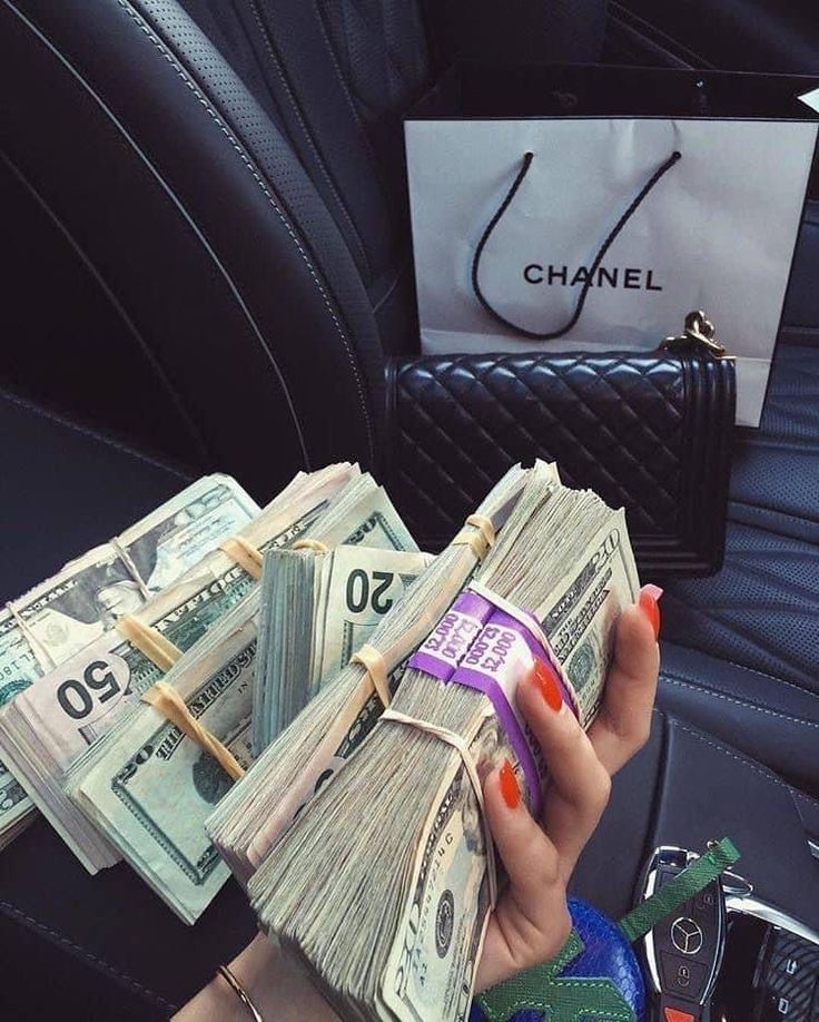 a woman is holding cash in her hand while sitting in the back seat of a car