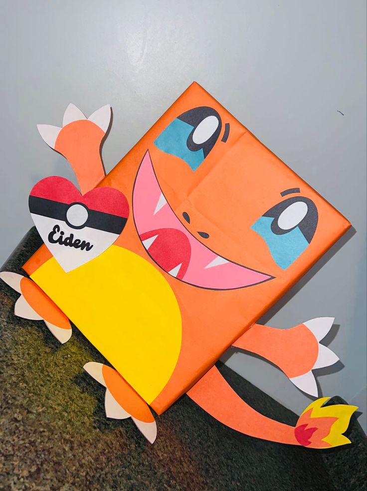 an orange and yellow paper cut out of a cartoon character with eyes, nose, mouth and tail