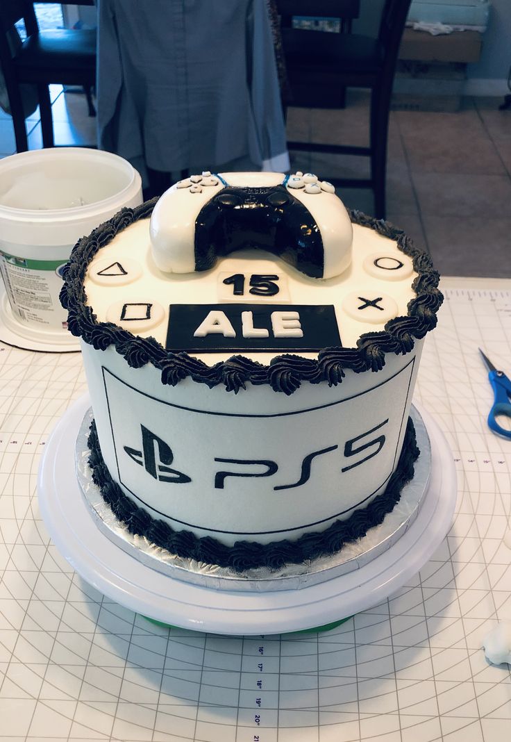 a white and black cake sitting on top of a table next to a pair of scissors