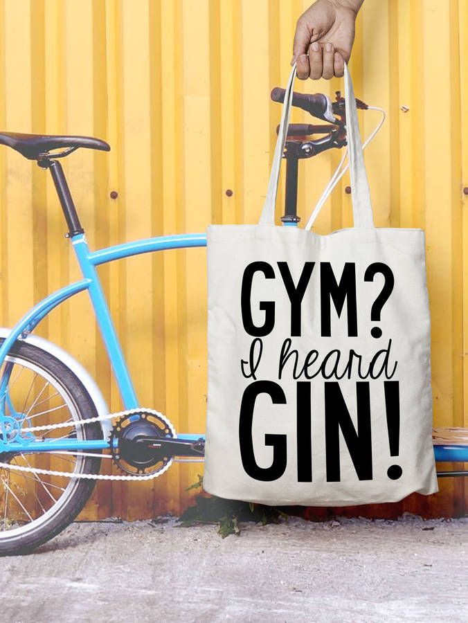 a person holding a gym tote bag next to a bicycle with the words gym? i heard gin on it