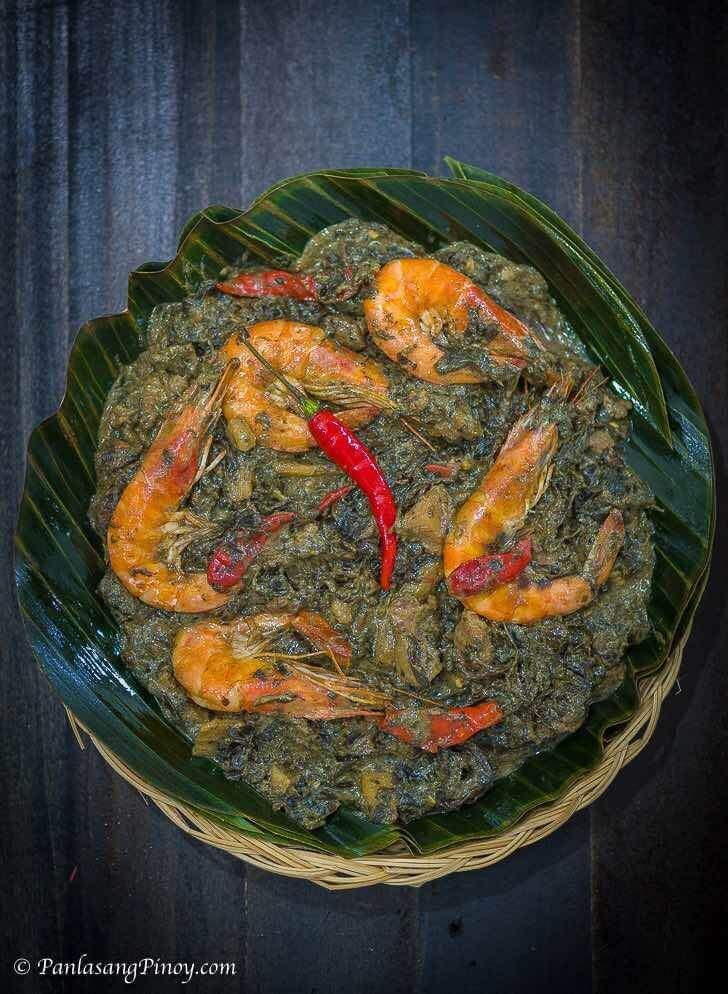 a bowl filled with shrimp and spinach on top of a green leafy plate