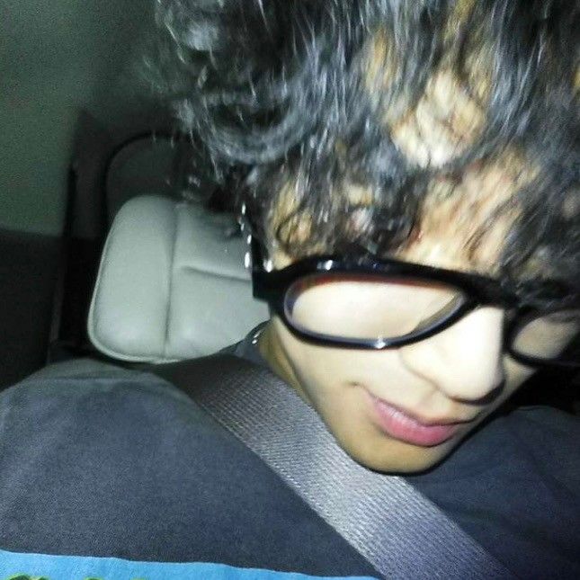 a close up of a person wearing glasses in the back seat of a car,