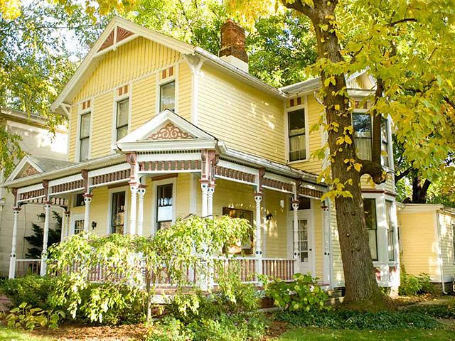 a large yellow house sitting next to a tree