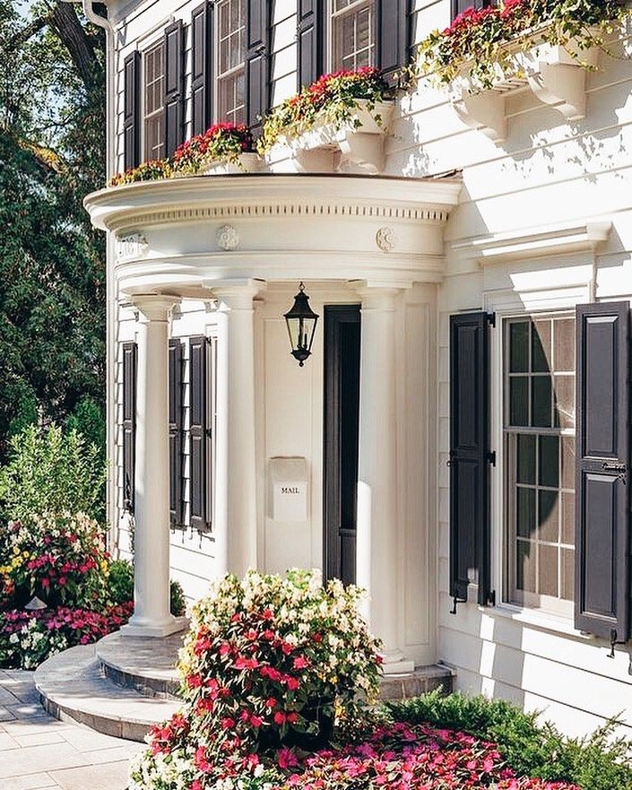 a white house with black shutters and flowers