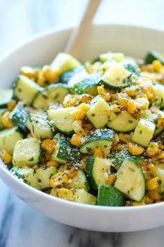 a white bowl filled with cucumber and corn salad on top of a table