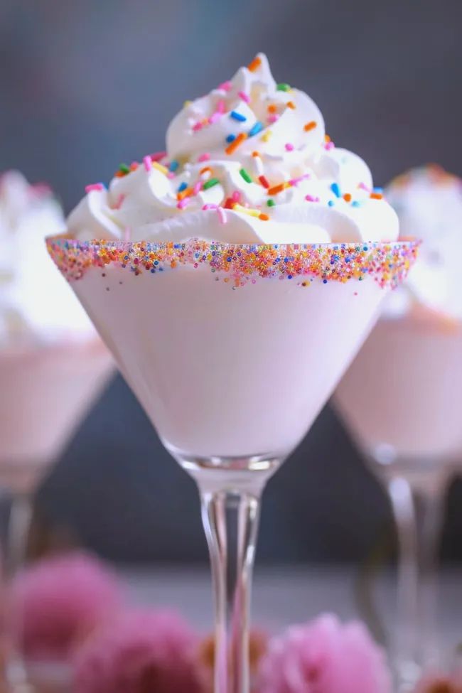 three glasses filled with whipped cream and sprinkles on top of each other