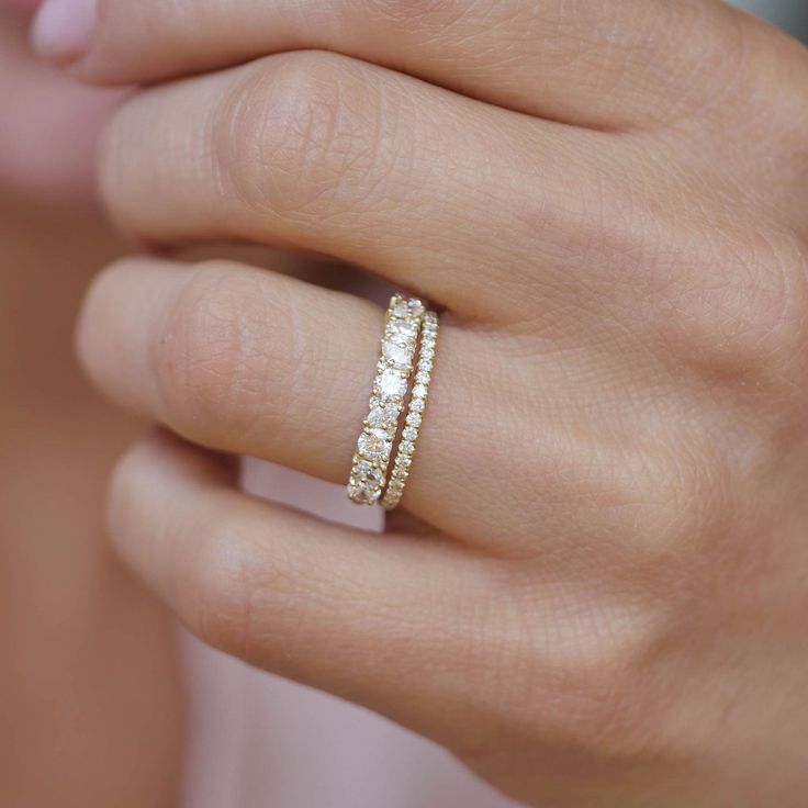 a woman's hand wearing a gold ring with three rows of diamonds on it