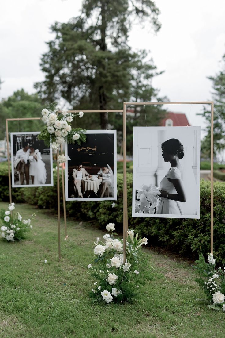 wedding pictures are hung on gold frames in the grass with flowers and greenery around them