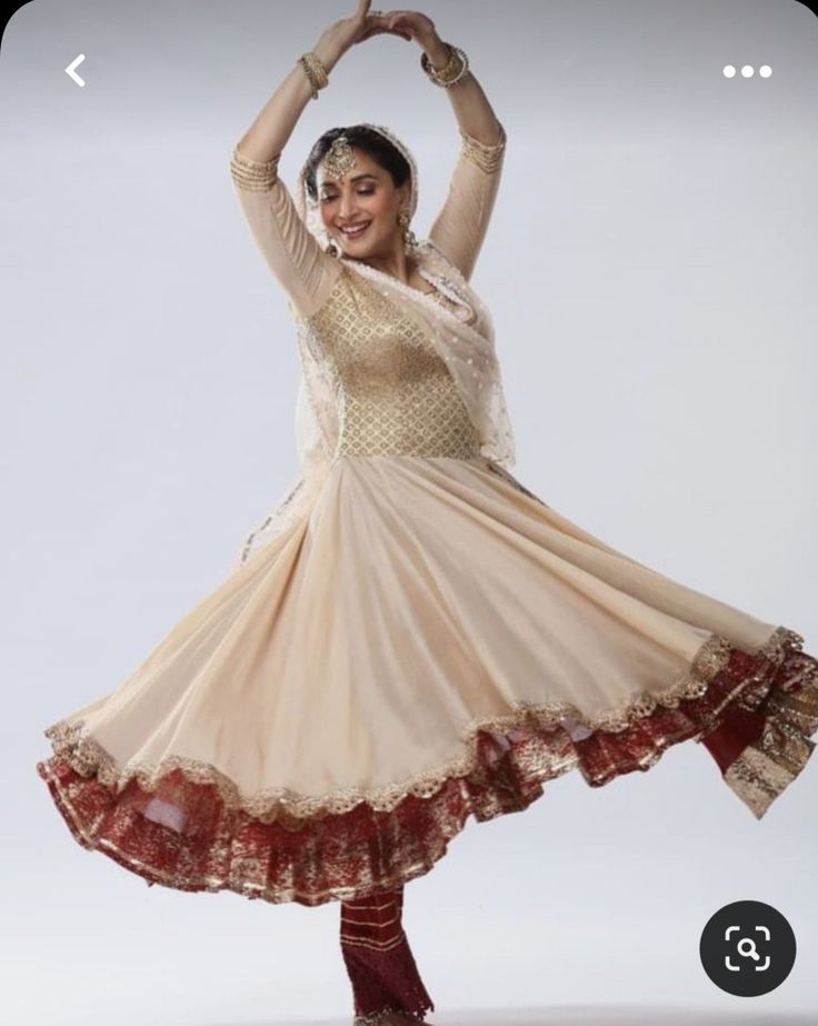 a woman in a white and red dress is doing a dance pose with her hands up