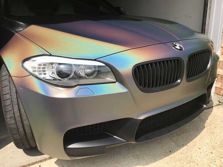 a metallic bmw car is parked in front of a garage