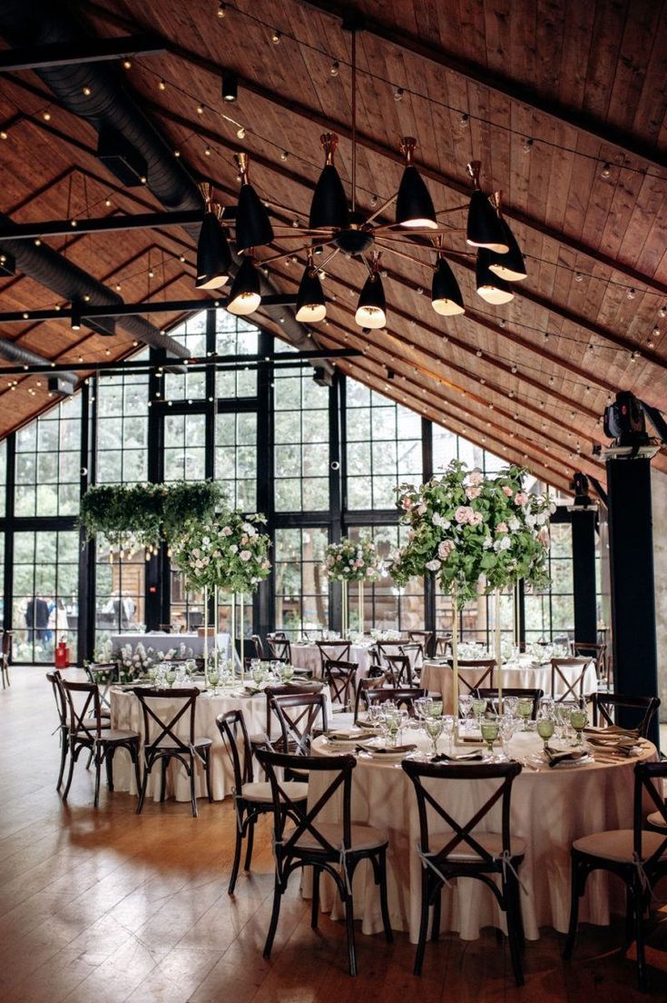 a large room with tables and chairs set up for a formal function in front of huge windows