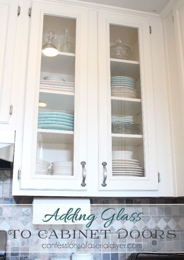 a kitchen with white cabinets and glass front cupboards filled with dishes on top of each cabinet