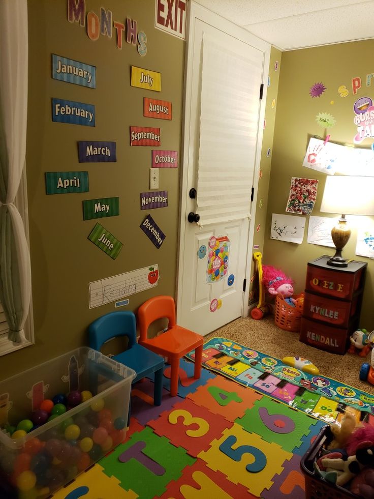 a child's playroom with toys and letters on the wall