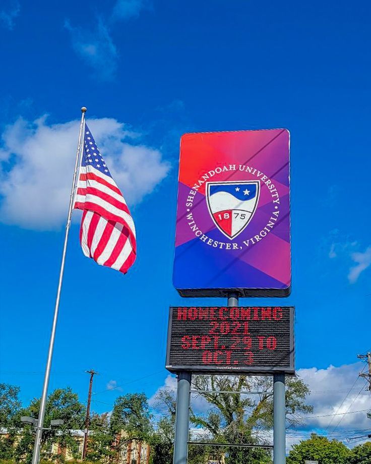 two flags are flying in the wind next to a sign that reads memorial united states university