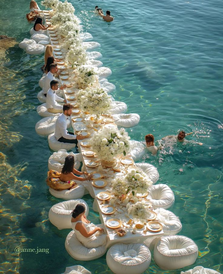 several people are sitting on inflatable chairs and floating flowers along the water's edge