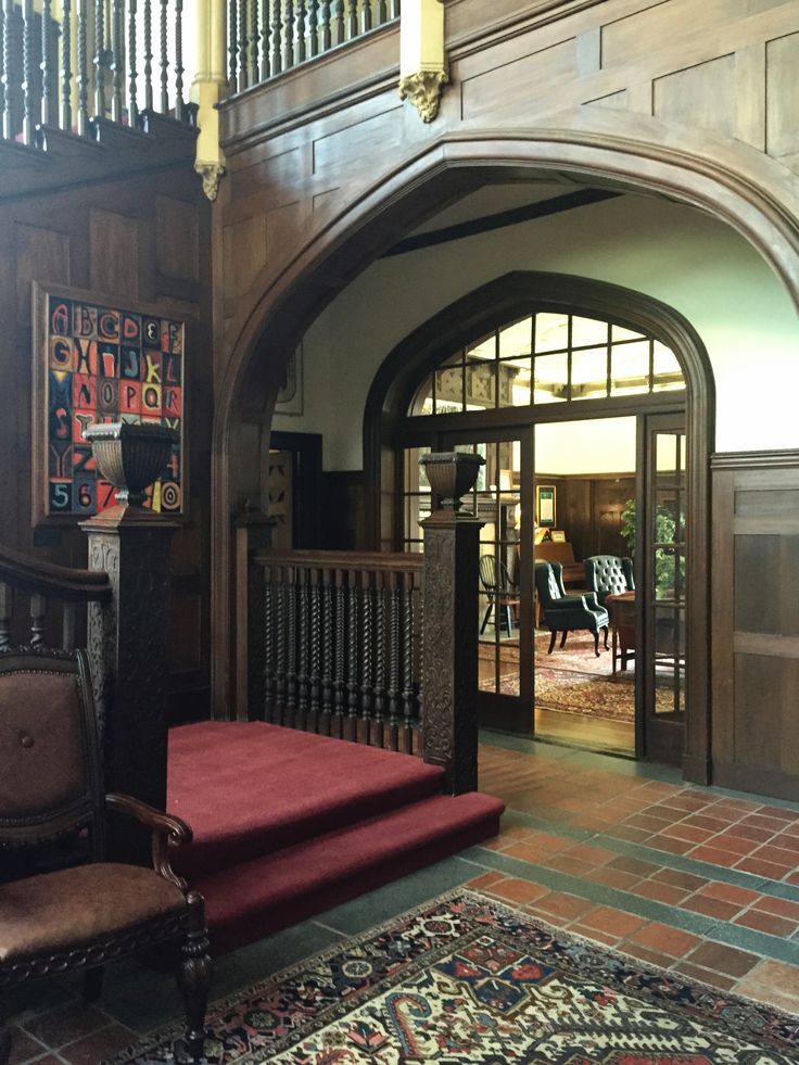 an ornate entry way with wooden paneling and red carpet on the floor next to a stair case