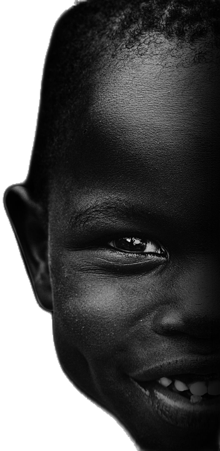 a black and white photo of a young boy with his eyes wide open, smiling