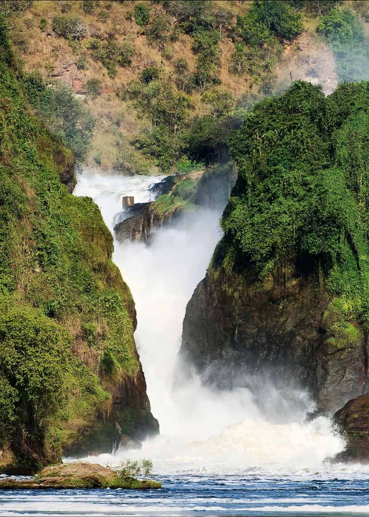 the waterfall is surrounded by lush green trees and water cascading down it's sides