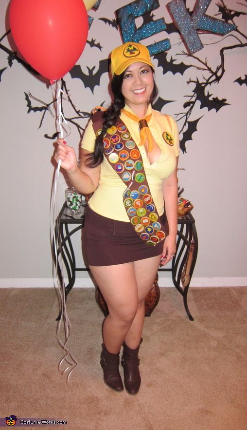 a woman dressed in costume holding a red balloon and wearing a yellow shirt with the word i love you written on it