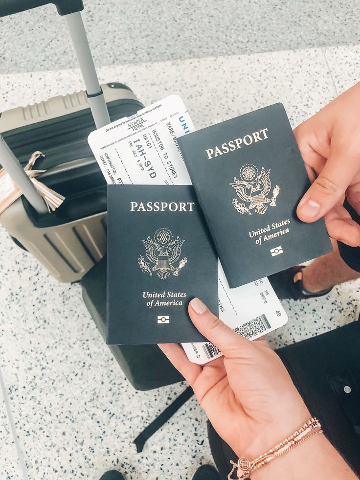 two people are holding their passports in front of the luggage bag at an airport terminal