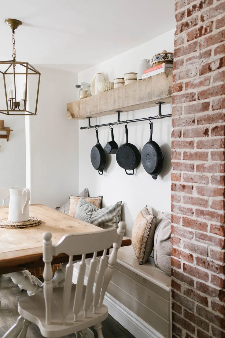 a wooden table sitting next to a brick wall with pots and pans on it