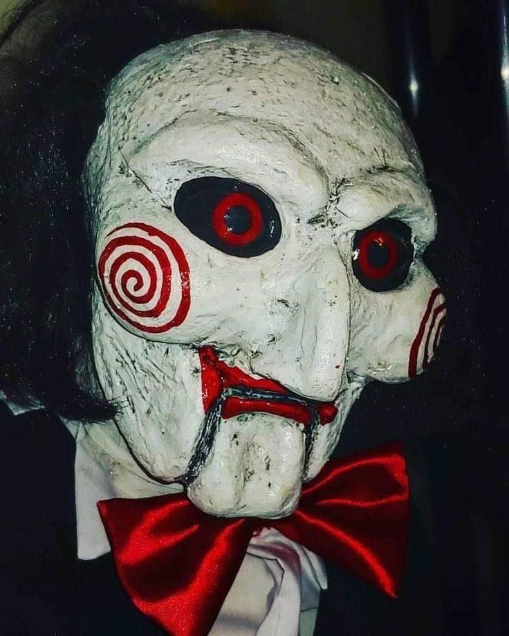 a creepy mask wearing a red bow tie