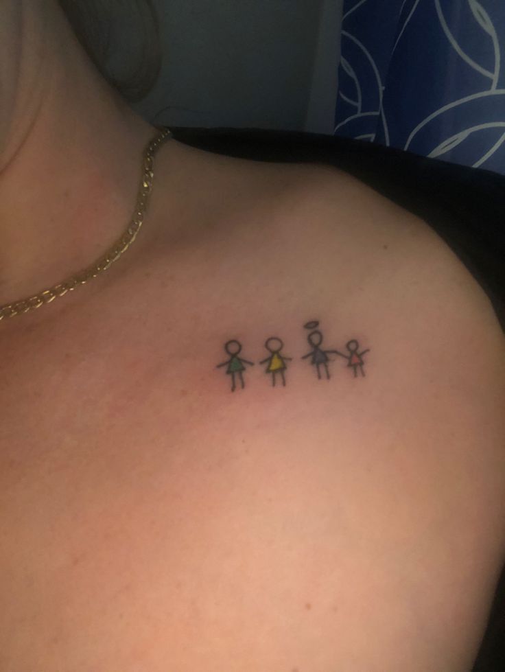 a woman's chest with three small stick figures on the back of her shoulder