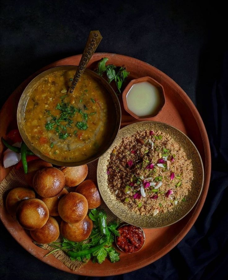 a plate topped with different types of food on top of a black table next to a bowl of soup