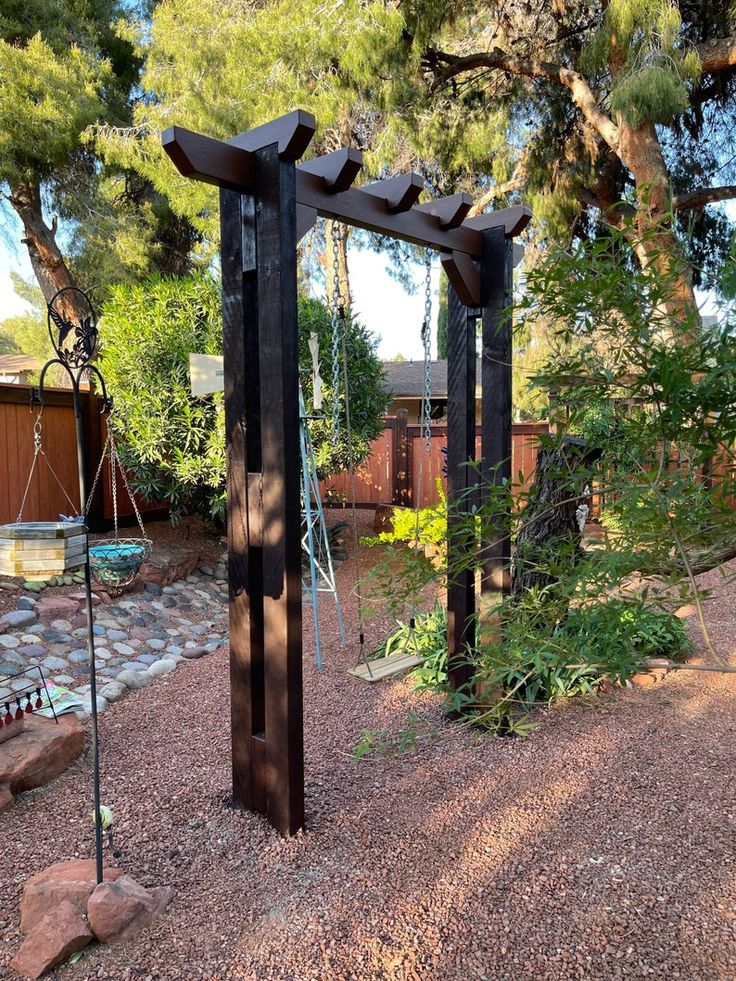 a wooden structure sitting in the middle of a garden next to a rock path and trees