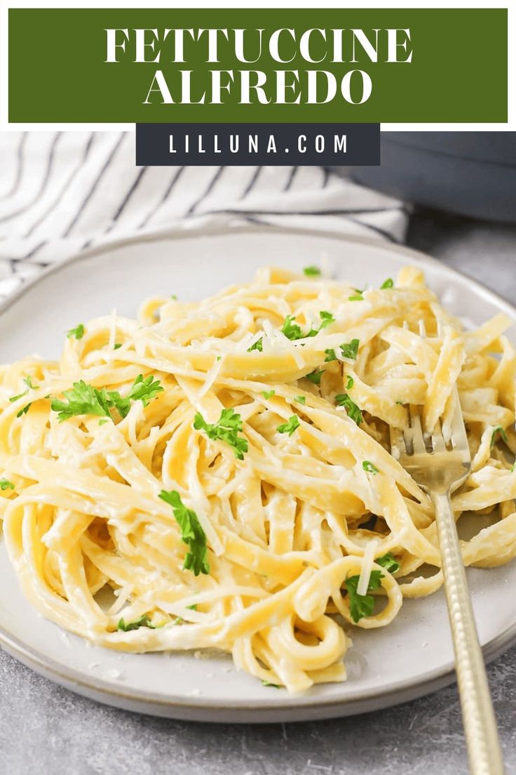 a white plate topped with pasta and parsley on top of a gray tablecloth