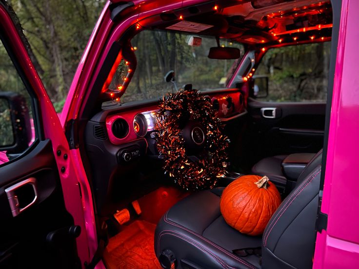 the interior of a pink truck with pumpkins in the passenger seat and lights on