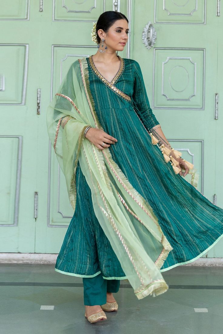 Emerald green chanderi blend angarkha with intricate sequin details, overlap panel and lace work. Paired with pants and blue light green organza dupatta with fringe lace border.
Component: 3
Pattern: Embroidered
Type Of Work: Gota and Sequin Work
Neckline: Surplice Neck
Sleeve Type: Three Quarter
Fabric: Angarkha: Chanderi Blend, Dupatta: Organza
Color: Green
Other Details: 
Side tassel tie-up on kurta
Gota work details on dupatta
Occasion: Puja,Haldi and Mehendi - Aza Fashions Gota Work, Organza Dupatta, Lace Border, Fashion App, Set For Women, Aza Fashion, Sleeve Type, Blue Light, Three Quarter