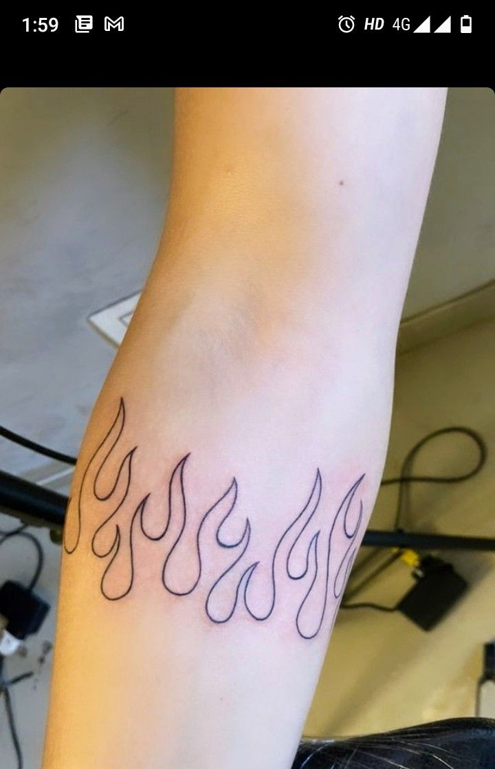 a person with a tattoo on their arm that has flames coming out of the top