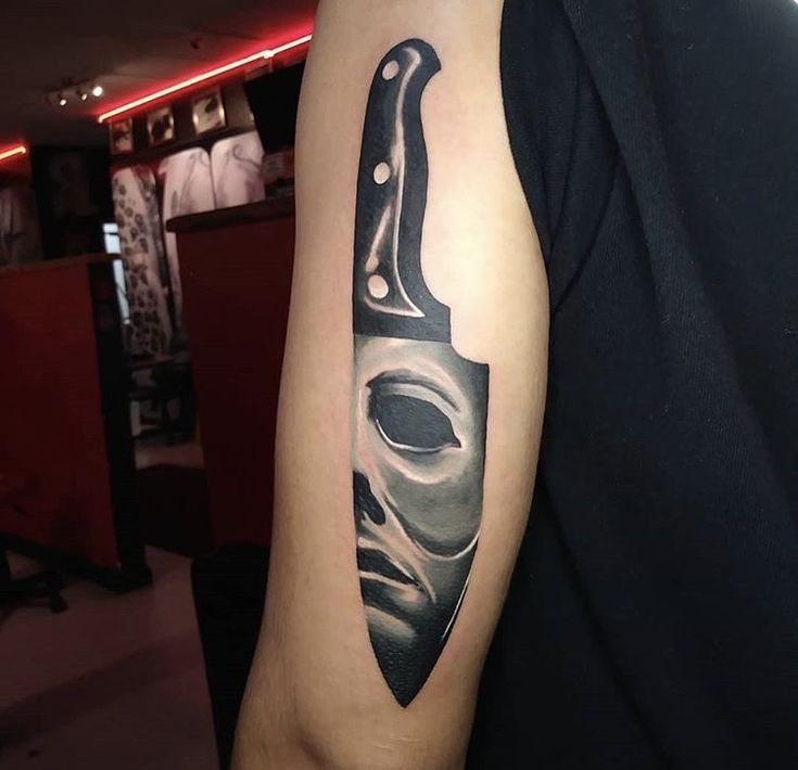 a man with a knife tattoo on his arm