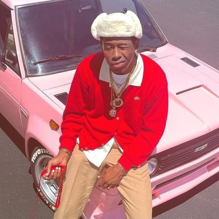 a man sitting on the hood of a pink car