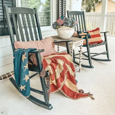 two rocking chairs on the front porch with an american flag blanket