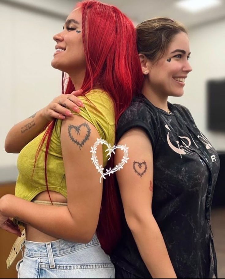 two girls with tattoos on their arms hugging each other