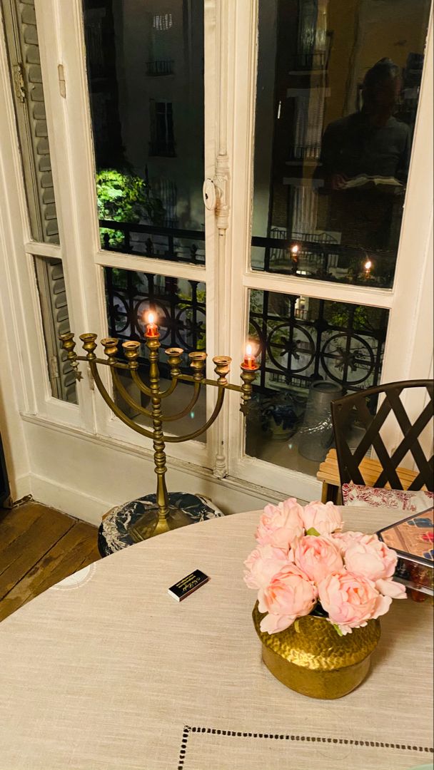 a table with flowers and candles on it in front of a window that looks out onto the street