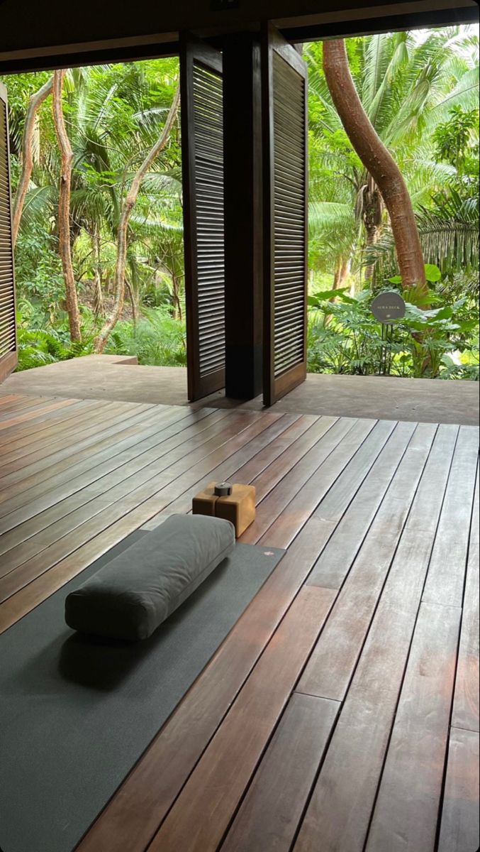 a yoga mat on a wooden deck in front of an open door with trees outside