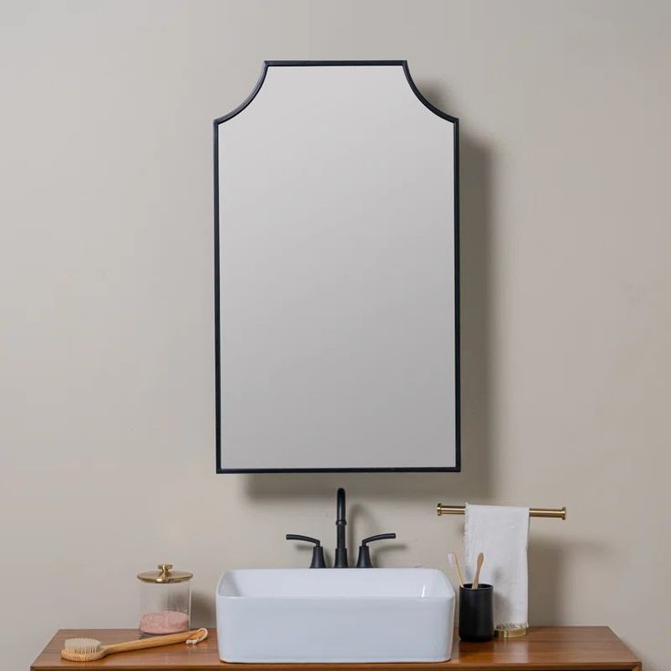 a bathroom sink sitting under a mirror next to a wooden counter with a toothbrush